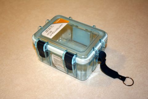1984 Ford Bronco - A clear plastic watertight box with blue latches and a black strap is shown on a textured surface.