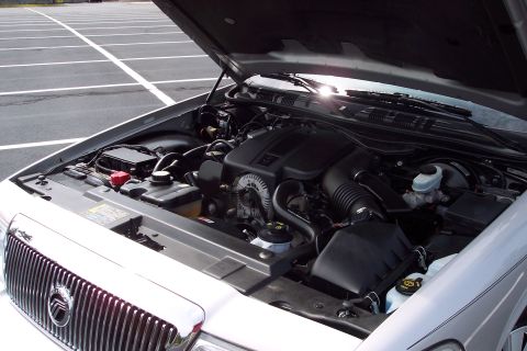 2001 Ford Crown Victoria - The engine bay of a silver 2004 Mercury Grand Marquis is shown with the hood open.