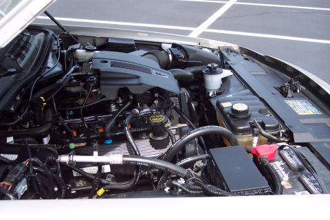 2001 Ford Crown Victoria - The engine compartment of a car is shown with various mechanical parts and wiring harnesses.