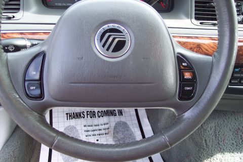 2001 Ford Crown Victoria - Interior view of a Mercury Grand Marquis steering wheel and dashboard, with a paper floor mat.