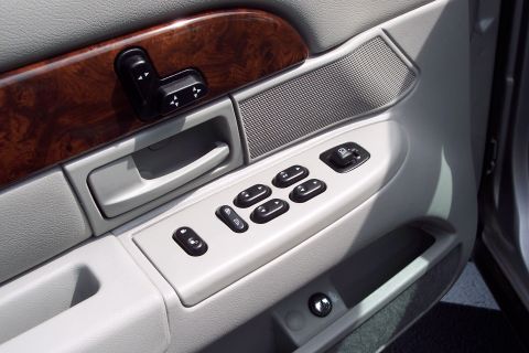 2001 Ford Crown Victoria - Close-up of a car's interior door panel, showing the window controls and wood grain accents.