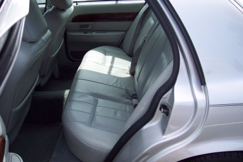 2001 Ford Crown Victoria - The interior of a silver sedan shows light gray leather seats and door panels with wood trim accents.