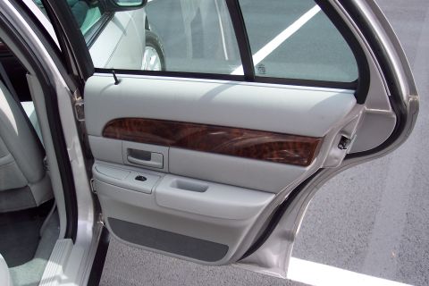 2001 Ford Crown Victoria - The interior door panel features wood trim and gray upholstery, with the rear door open.
