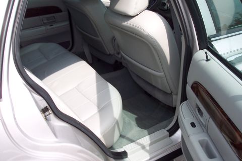 2001 Ford Crown Victoria - Rear passenger area of a car, showing light-colored leather seats and door trim.