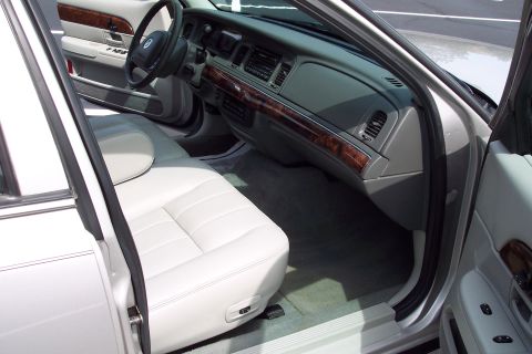 2001 Ford Crown Victoria - The interior of a 2001 Ford Crown Victoria features white leather seats and wood grain trim accents on the dashboard and doors.