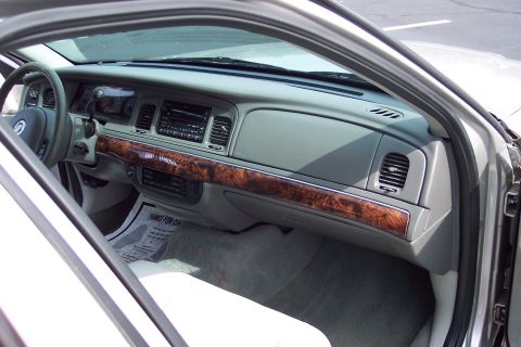2001 Ford Crown Victoria - Dashboard and interior of a car, showing wood trim and a floor mat.
