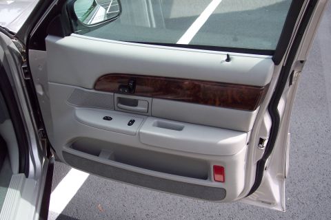 2001 Ford Crown Victoria - The interior door panel shows light gray upholstery, wood grain trim, and power controls.