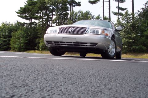 2001 Ford Crown Victoria - A silver Mercury Grand Marquis is parked on the side of the road, viewed from a low angle.