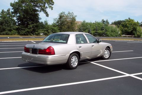 2001 Ford Crown Victoria - This silver sedan is parked in a lot with trees in the background.