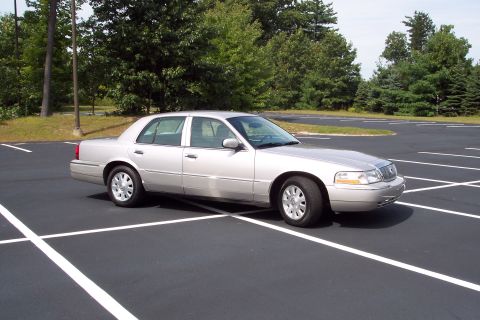 2001 Ford Crown Victoria - This silver 2004 Mercury Grand Marquis is parked in an empty lot under a clear sky.