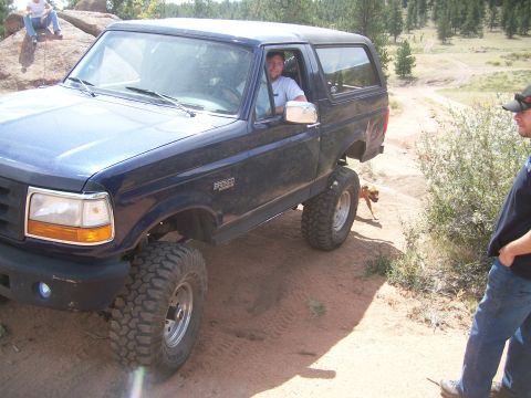 1993 Ford Bronco - Blue 1993 Ford Bronco driving off-road with people watching.