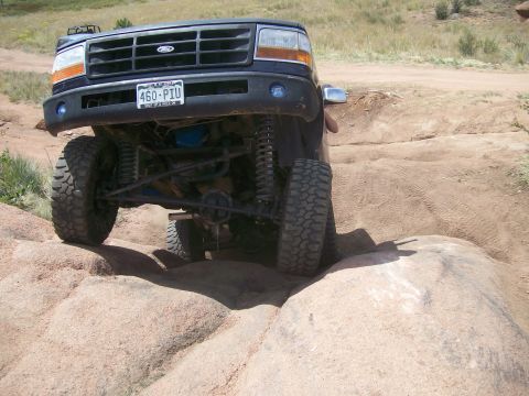 1993 Ford Bronco - A black 1992 Ford Bronco navigates a rocky off-road course, demonstrating its suspension and tire grip.