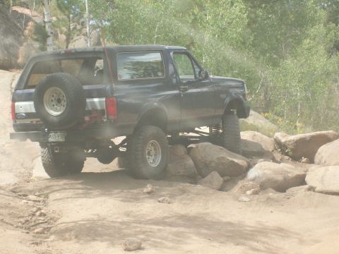 1993 Ford Bronco - Ford Bronco tackling difficult terrain on a rocky off-road path.