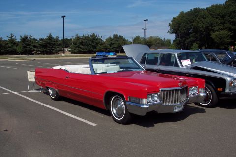 2001 Ford Crown Victoria - A red convertible Cadillac is parked in a lot next to other vehicles, with its hood open.