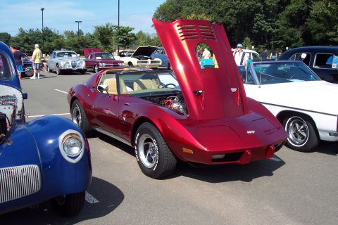 2001 Ford Crown Victoria - A shiny red Chevrolet Corvette is displayed with its hood open at an outdoor car show.