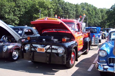 2001 Ford Crown Victoria - A vintage red and black tow truck is parked at a show, with other vehicles visible in the background.