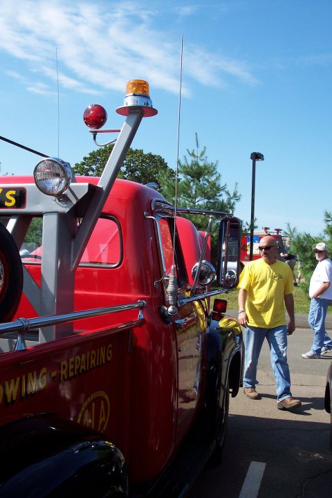 2001 Ford Crown Victoria - A red tow truck is parked at an outdoor event with people nearby.