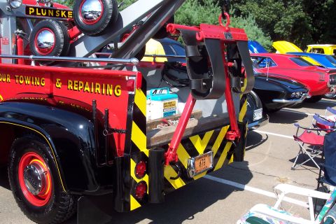 2001 Ford Crown Victoria - A vintage tow truck with "OUR TOWING & REPAIRING" painted on its side is parked at a show with other vehicles visible.