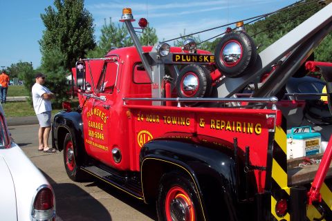 2001 Ford Crown Victoria - This tow truck has 'PLUNSKE'S GARAGE' and '24 HOUR TOWING & REPAIRING' text on its side.