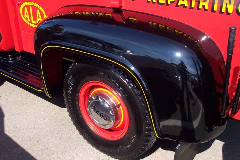 2001 Ford Crown Victoria - Close-up of a vintage Ford truck's fender and wheel, showing red paint and black accents.