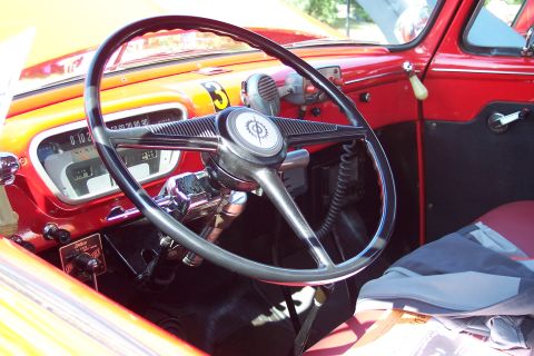 2001 Ford Crown Victoria - The interior of a vintage red truck features a large steering wheel and a dashboard with a visible number 3.