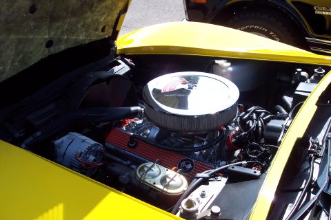 2001 Ford Crown Victoria - Engine bay of a yellow car, showing the air cleaner and valve covers. Another vehicle is partially visible.