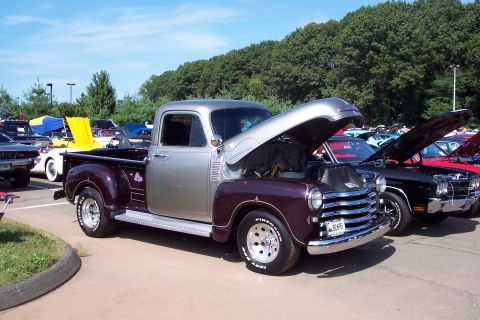 2001 Ford Crown Victoria - Maroon and silver pickup truck on display at a car show, hood up.