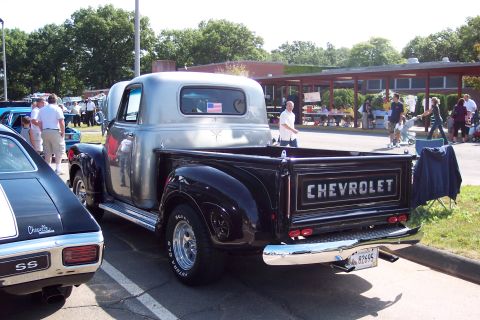 2001 Ford Crown Victoria - A classic black 1955 Chevrolet pickup truck is displayed at a show, with another car visible to the left.