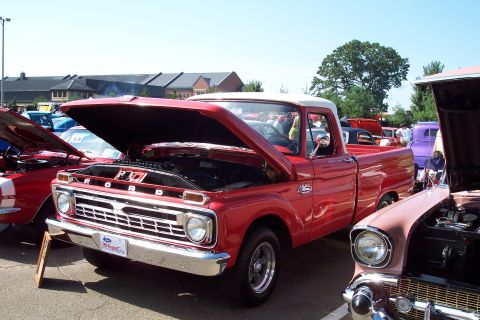 2001 Ford Crown Victoria - A red 1965 Ford pickup truck is displayed with its hood open at a car show, alongside other vehicles.