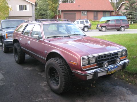 2000 Ford E350 - Maroon AMC Eagle wagon with off-road tires and roof rack, parked next to other vehicles.