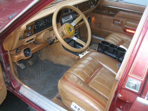 2000 Ford E350 - The interior of a vintage car features brown leather seats and a wood-grain dashboard with a cassette player.