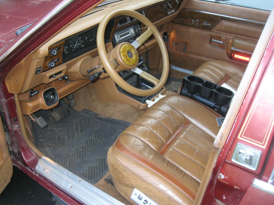 Tan interior of an old car, showing the dashboard, steering wheel, and front seats