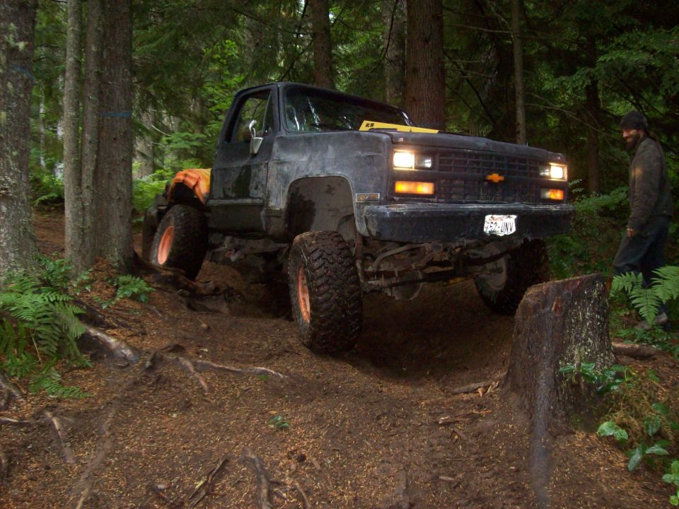 Black lifted pickup truck navigating a muddy forest trail