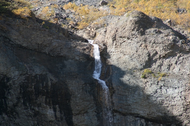 Waterfall cascading down a rocky cliff face with sparse vegetation
