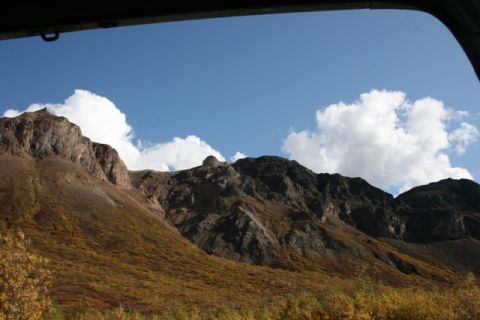 1990 Chevrolet Suburban - Mountain landscape with autumn colors and clouds, viewed from a vehicle window.