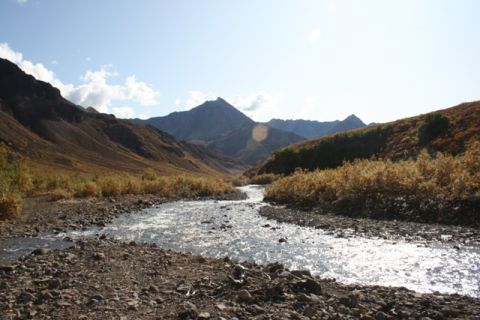 1990 Chevrolet Suburban - A scenic view of a river winding through a valley with mountains in the background under a clear sky.