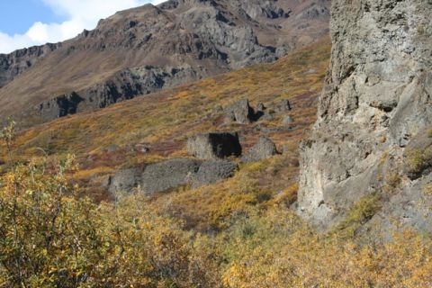 1990 Chevrolet Suburban - Mountain landscape with autumn foliage and rocky outcrops under a blue sky.
