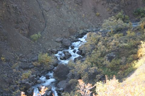 1990 Chevrolet Suburban - A scenic view of a mountain stream cascading over rocks in a gorge during autumn.