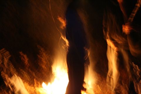 1990 Chevrolet Suburban - Figures gather around a bright bonfire, illuminated by the flames.