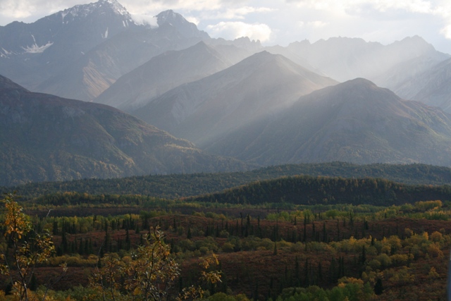Mountain range with forested valleys and peaks in the distance. Hazy sky