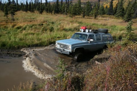 1990 Chevrolet Suburban - This 1990 Chevrolet Suburban navigates a challenging muddy terrain, equipped for off-road adventure.