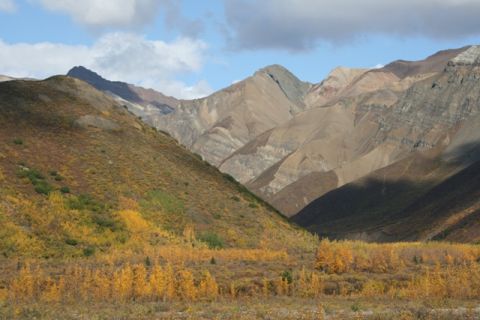 1990 Chevrolet Suburban - A scenic view of a mountain valley during autumn, with colorful foliage blanketing the slopes and a dramatic sky overhead.