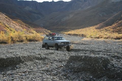 1990 Chevrolet Suburban - A K5 Blazer navigates a , rocky terrain under a vast mountain landscape.