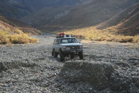 1990 Chevrolet Suburban - A Chevrolet Suburban navigates a , rocky terrain in a mountainous valley.
