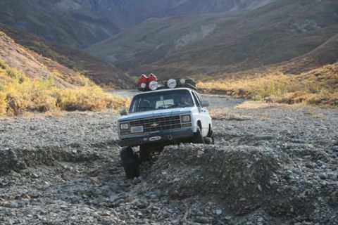 1990 Chevrolet Suburban - Chevrolet pickup truck navigates a challenging rocky path in a mountainous landscape.