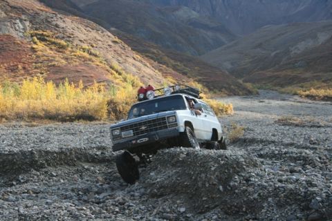 1990 Chevrolet Suburban - A white Chevrolet K5 Blazer tackles a challenging off-road terrain in a mountainous, autumnal landscape.