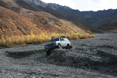 1990 Chevrolet Suburban - Chevrolet K5 Blazer tackles rough terrain in a mountainous landscape during autumn.