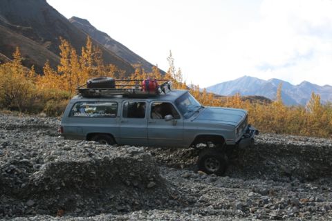 1990 Chevrolet Suburban - Chevrolet Suburban navigating a rocky trail with mountains in the background.