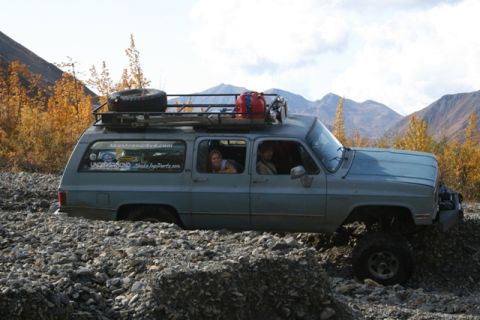 1990 Chevrolet Suburban - A gray Chevrolet Suburban navigates a challenging rocky path, equipped for an off-road adventure.