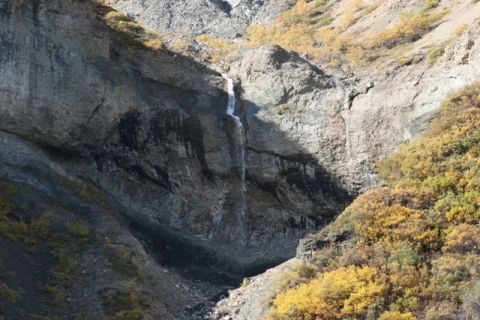 1990 Chevrolet Suburban - A waterfall tumbles down a steep, rocky mountainside during autumn.